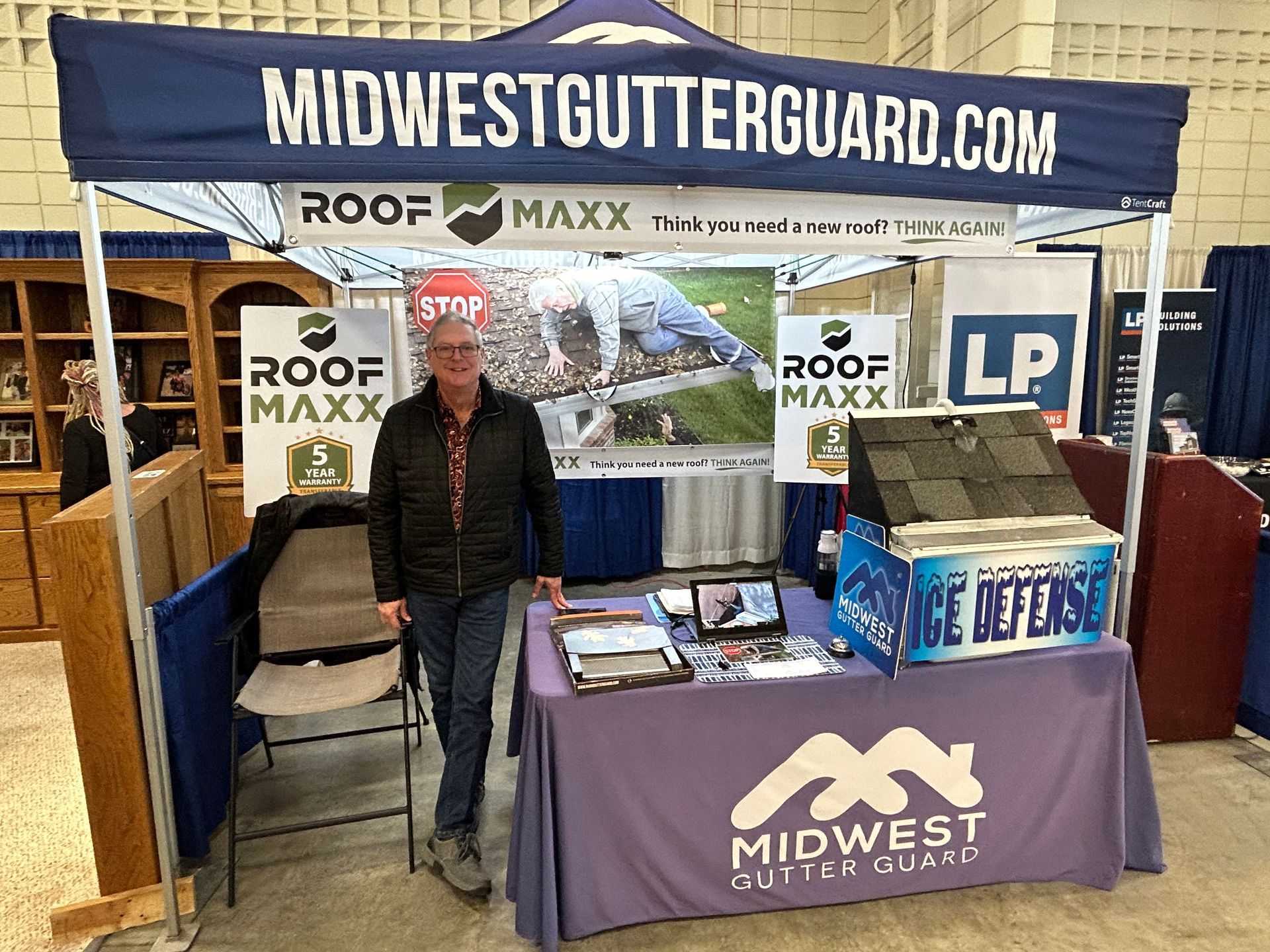 A man is standing in front of a booth at a trade show.