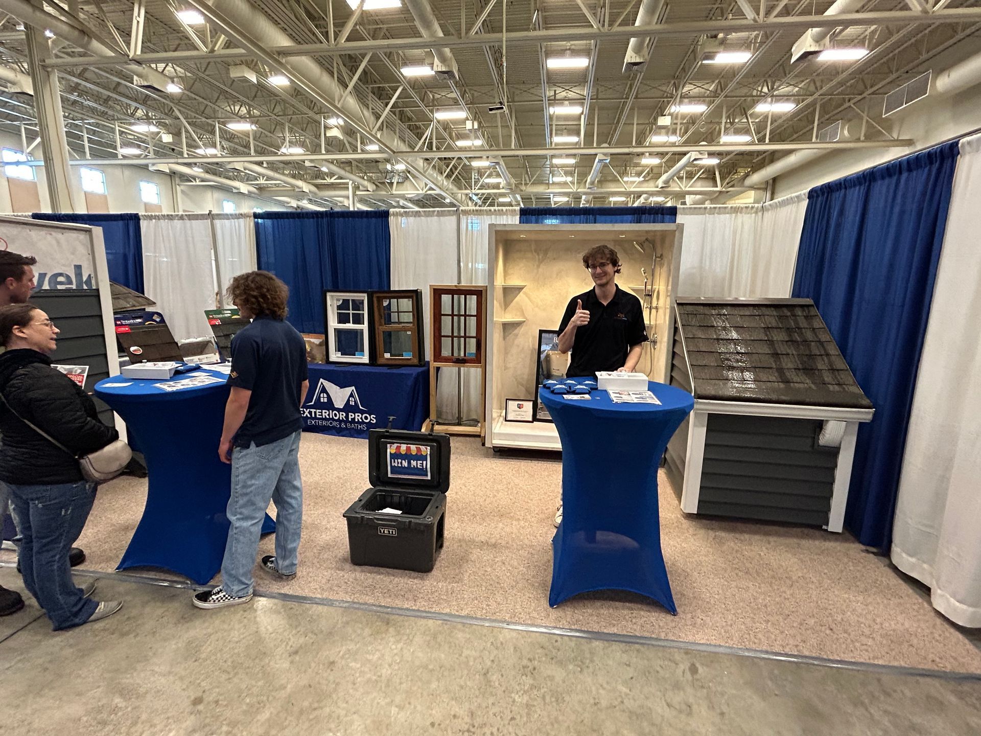 A group of people are standing around tables at a trade show.