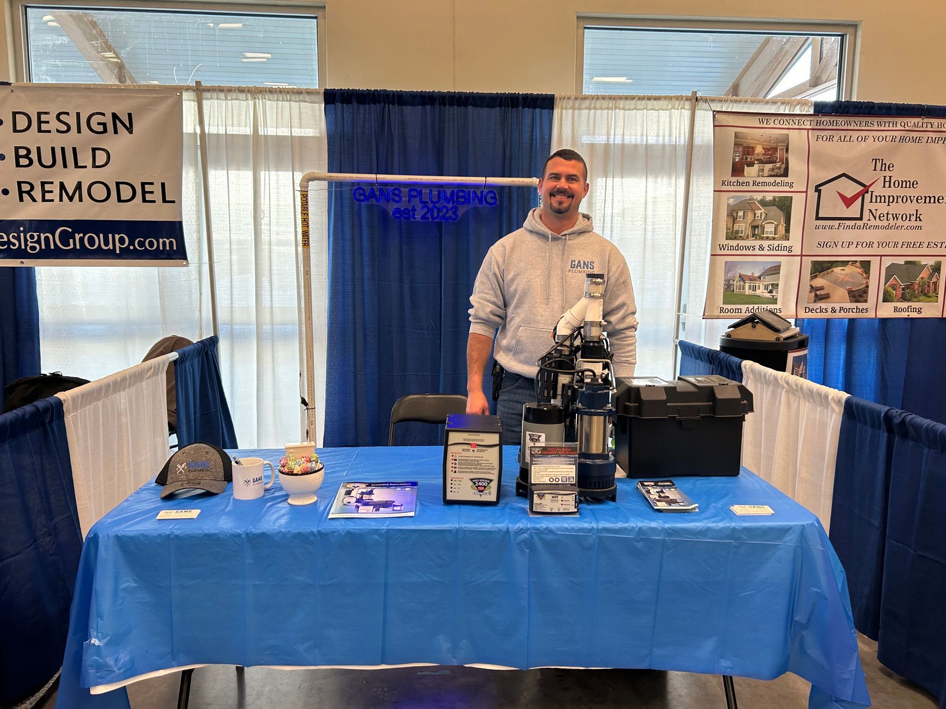 A man is standing in front of a table with a sign that says design build remodel.