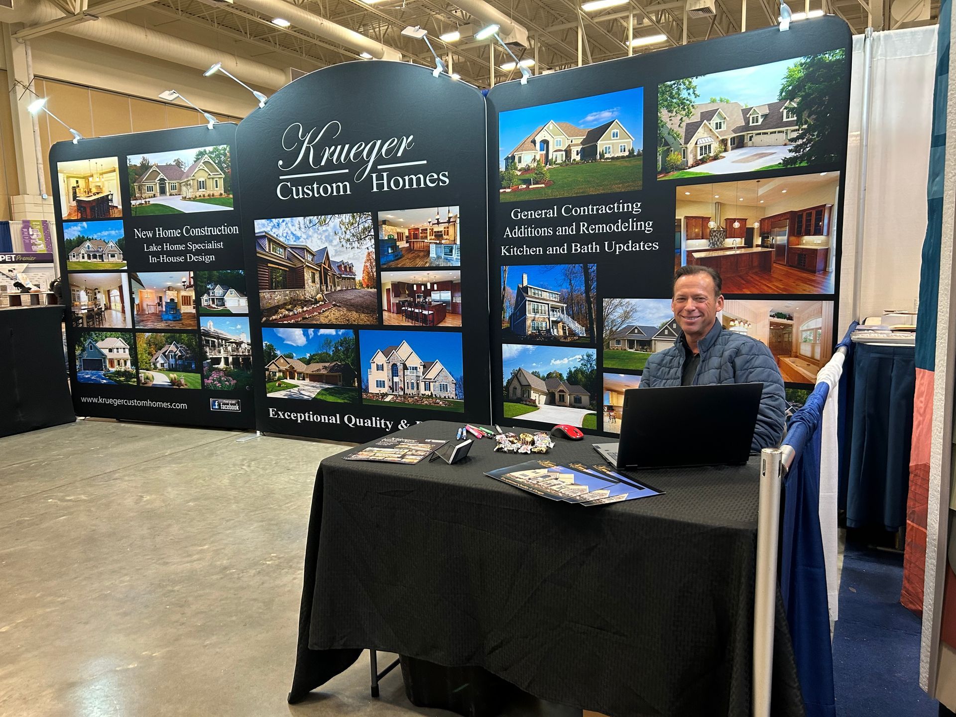 A man is sitting at a table in front of a wall with pictures of houses on it.