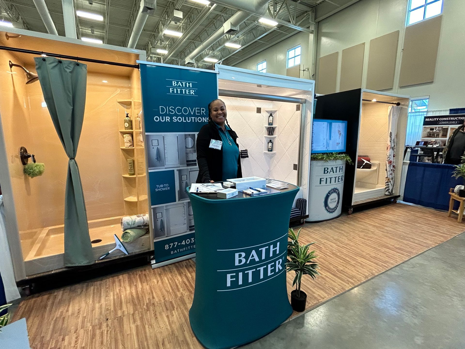 A man is standing in front of a booth at a convention.