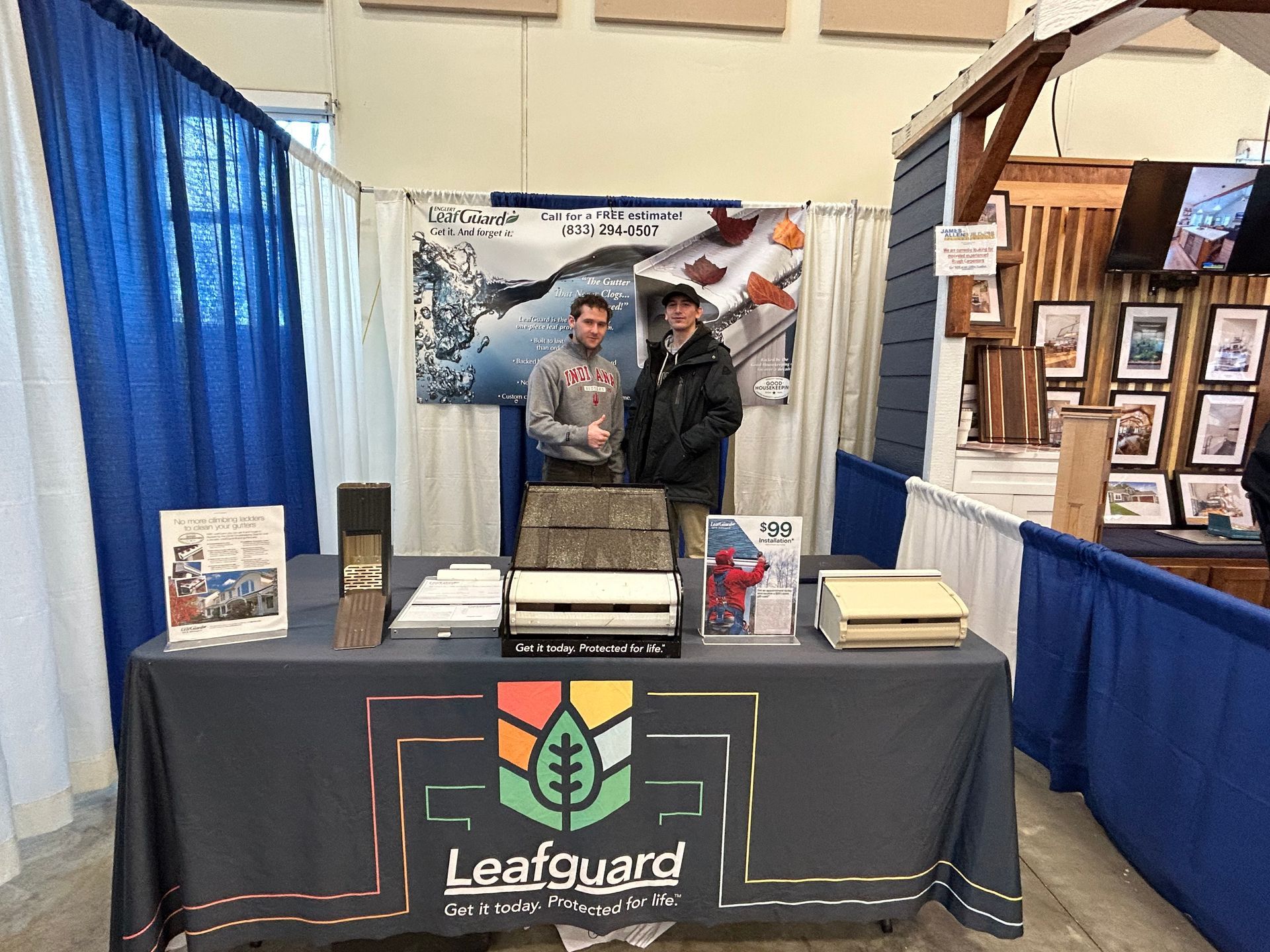 Two men are standing in front of a table that says leafguard