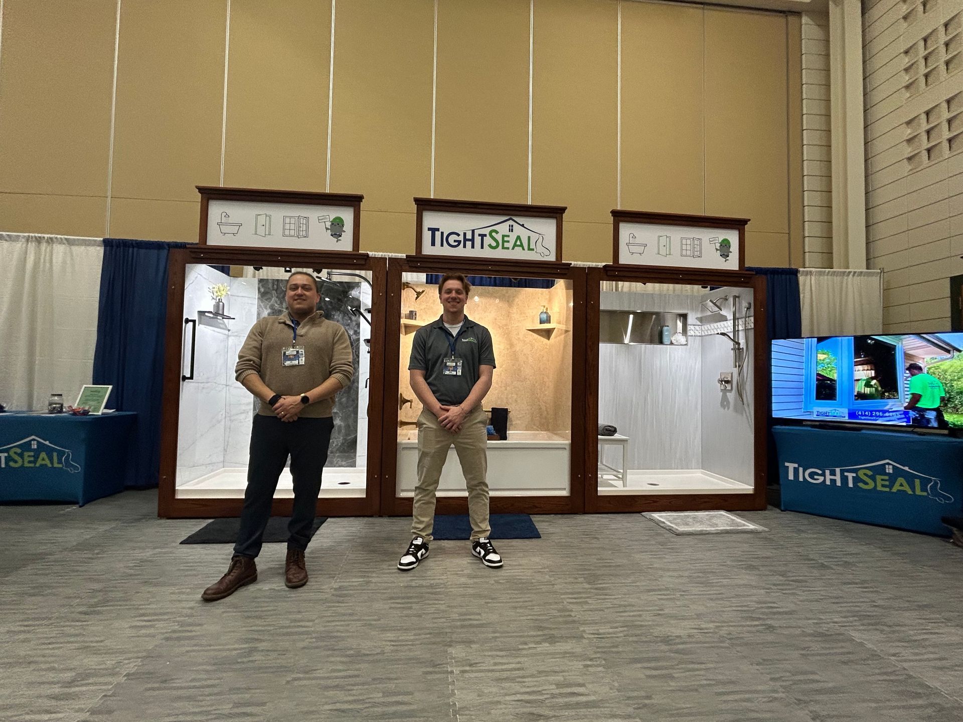 Two men are standing in front of a display of bathroom products.