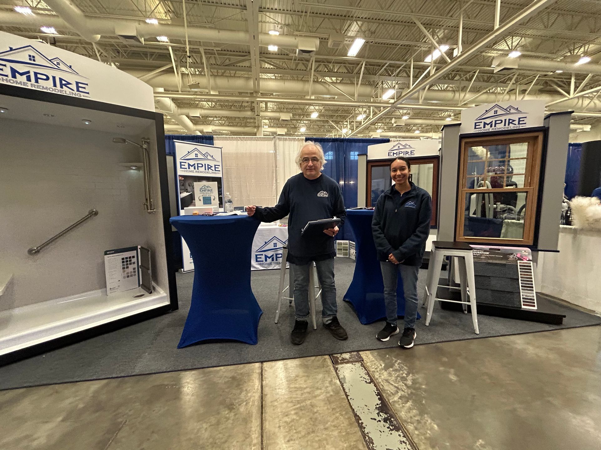 Two men are standing in front of a booth at a convention.