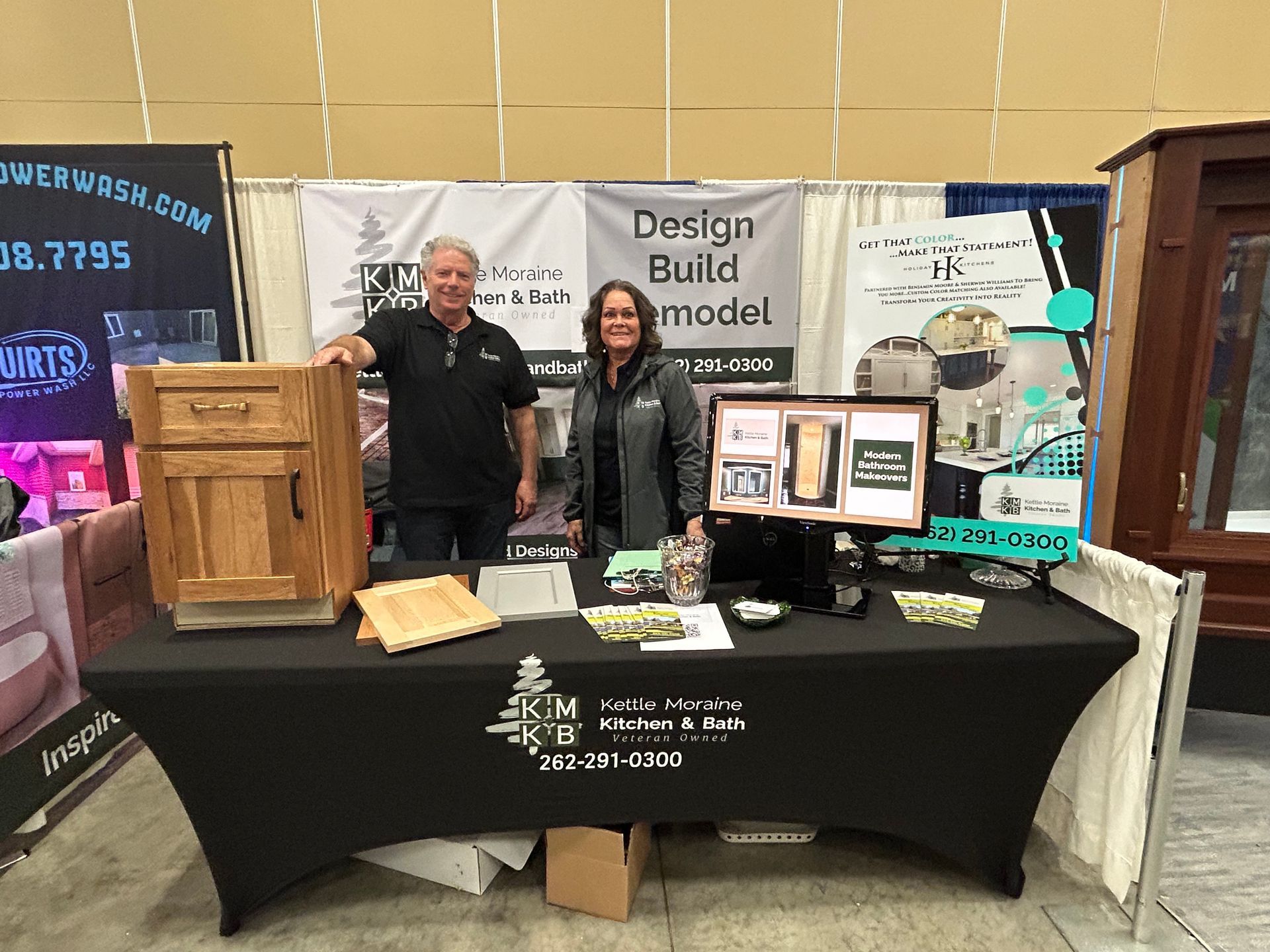 A man and a woman are standing at a table in front of a sign that says design build model.
