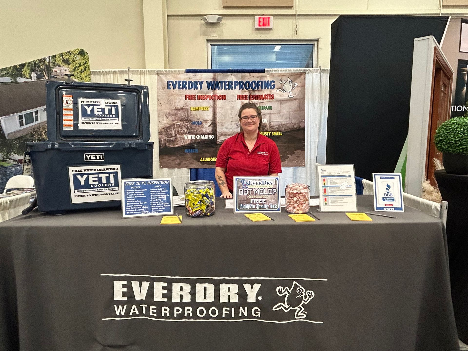 A woman is sitting at a table with a sign that says everdry waterproofing