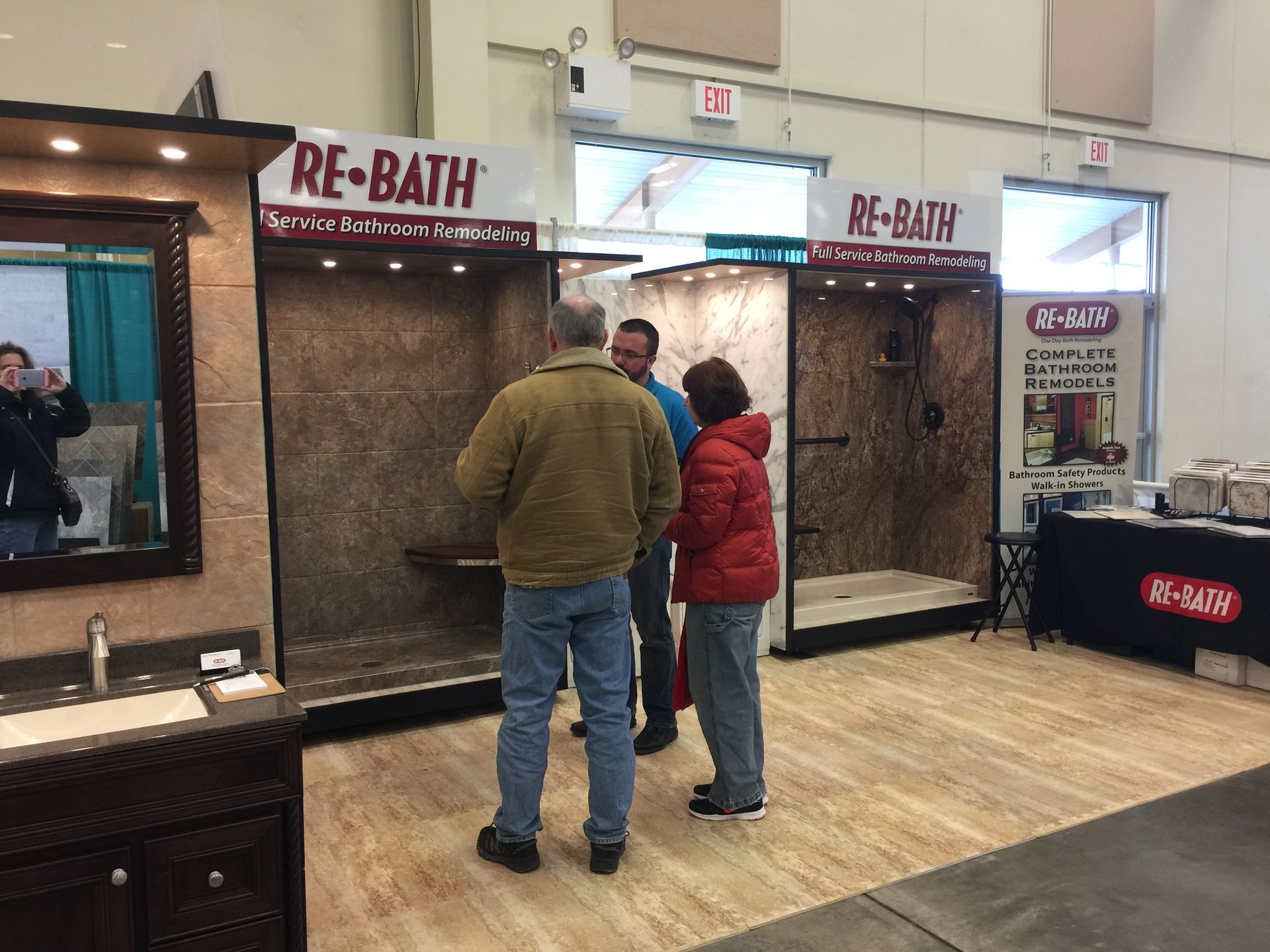 A group of people are standing in front of a re-bath display.