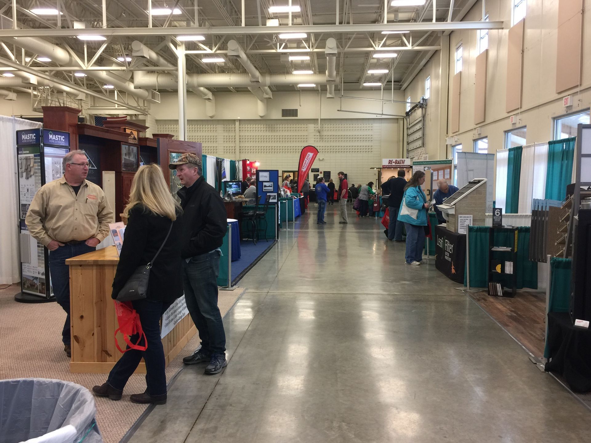A group of people are standing in a large room at a convention.