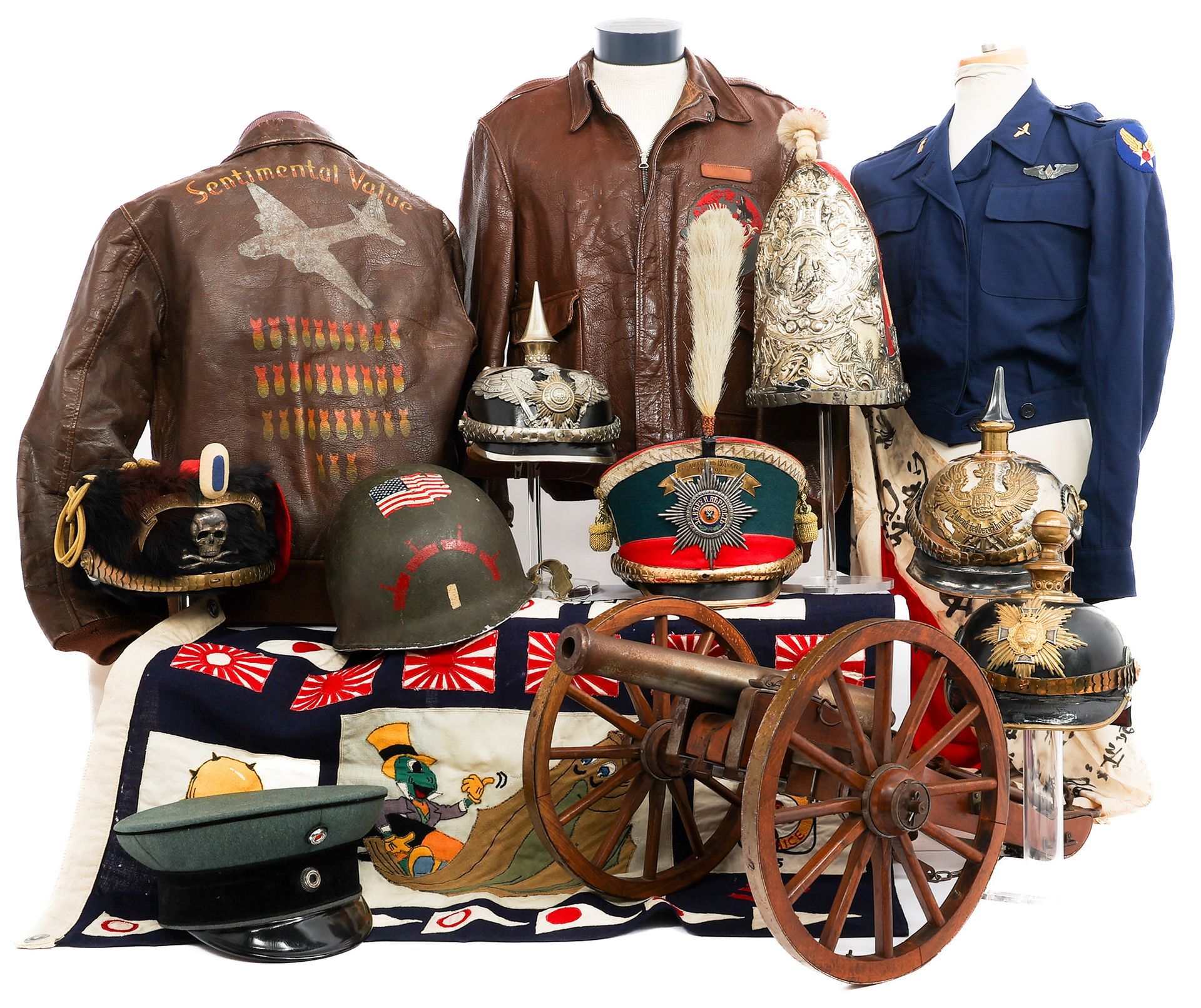 Collection of military uniforms, hats, a cannon, and a jacket on display.