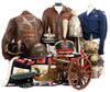 Collection of military uniforms, hats, a cannon, and a jacket on display.
