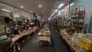Indoor shot of an antique market with various displays of vintage items and collectibles on tables.