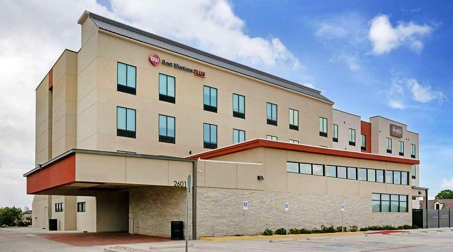 Hotel exterior with pool and lounge chairs. Blue sky overhead.