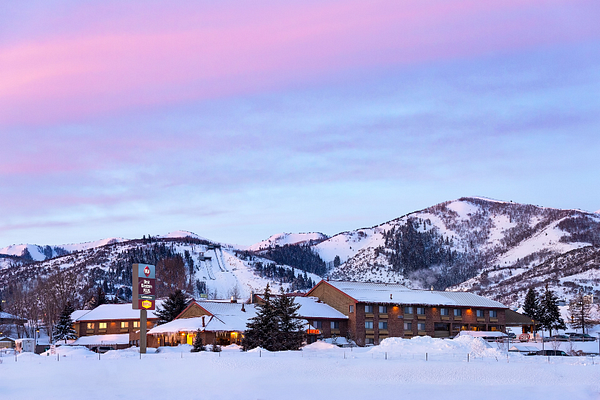 Hotel exterior with pool and lounge chairs. Blue sky overhead.
