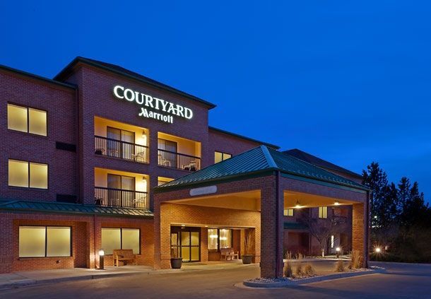 Hotel exterior with pool and lounge chairs. Blue sky overhead.