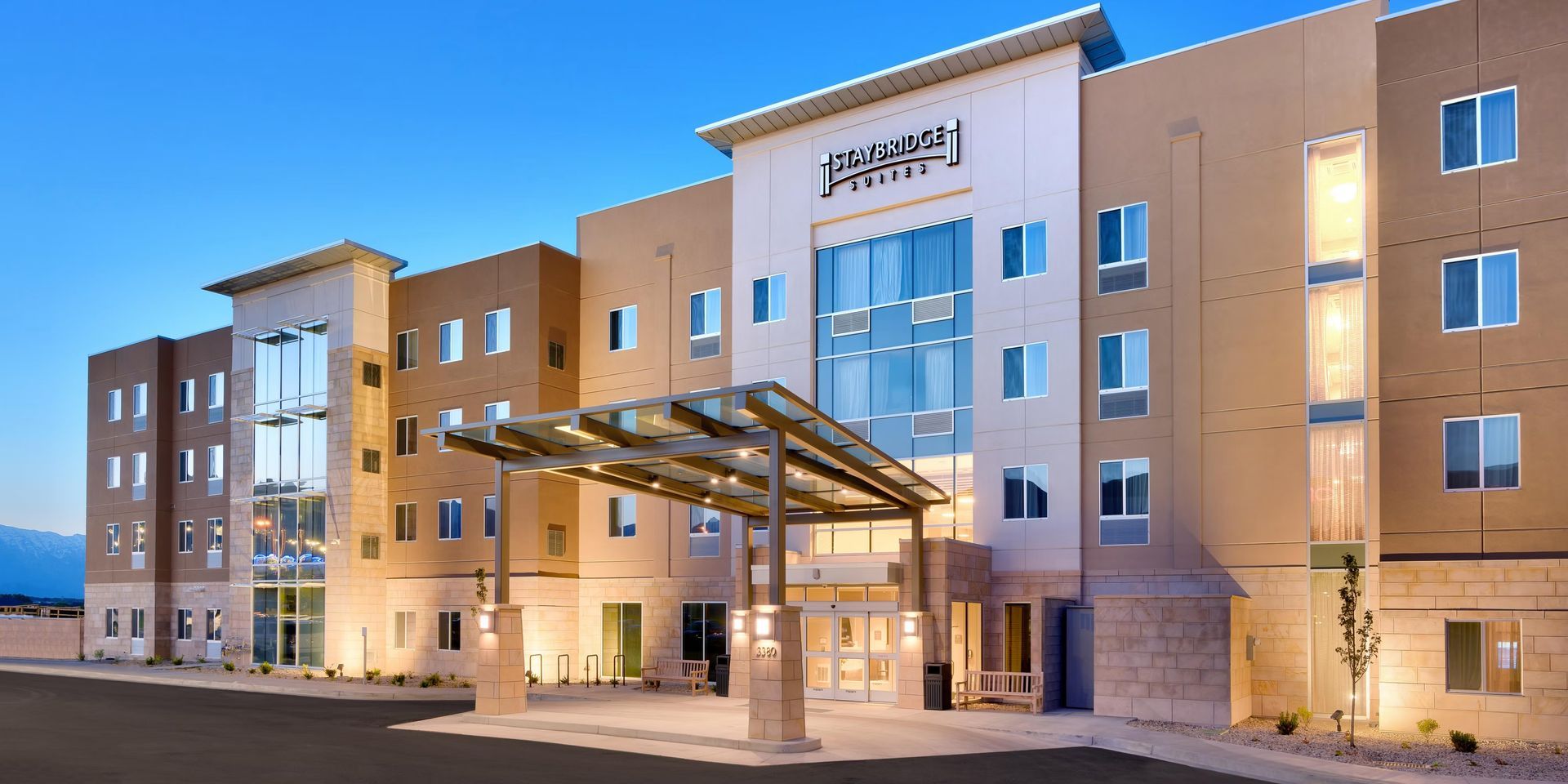 Hotel exterior with pool and lounge chairs. Blue sky overhead.