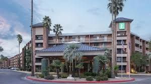 Hotel exterior with pool and lounge chairs. Blue sky overhead.