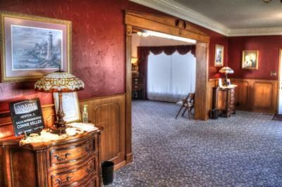 Elegant interior with red walls, wooden trim, and lamps. Opens to a room with white curtains.