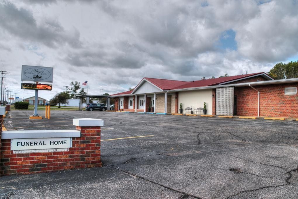 Exterior of a funeral home with a red brick facade, overcast sky. 