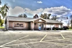 Meyer Funeral Home, brown building with a sign, blue sky, parking lot.