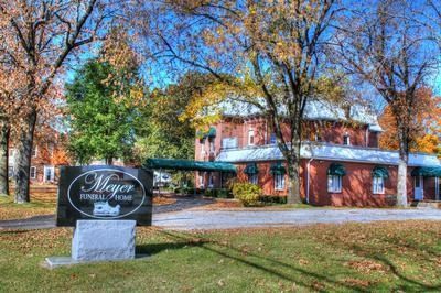 Meyer Funeral Home with sign in front of a red brick building, trees in autumn colors.
