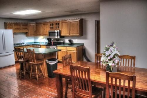 Kitchen with wooden cabinets, island with stools, and a dining table set for a meal.