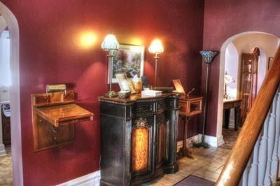 Burgundy entryway with antique desk and cabinet, lamps, and stairs.