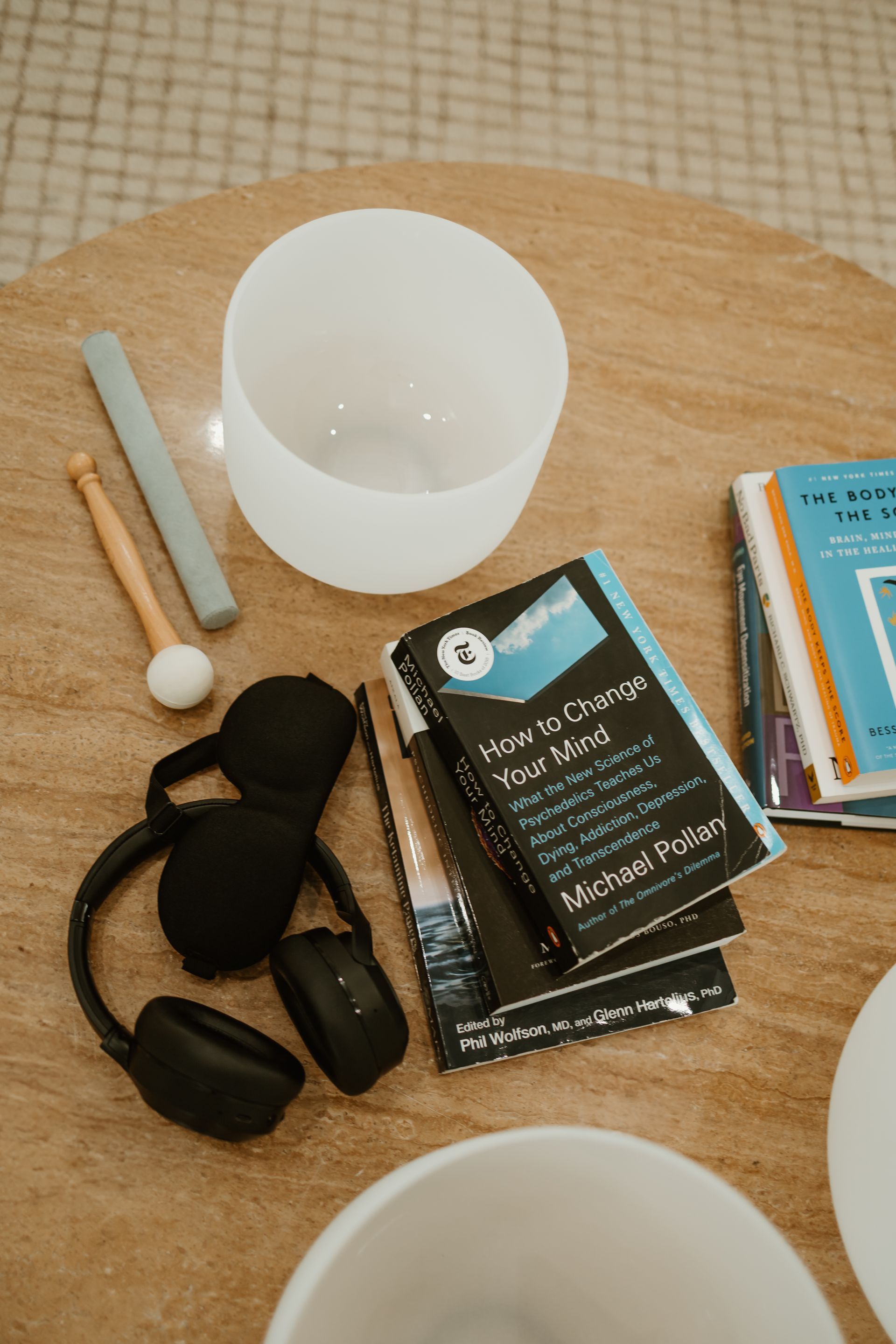 Assorted craft supplies on a round table, including cups, markers, books, and black items.