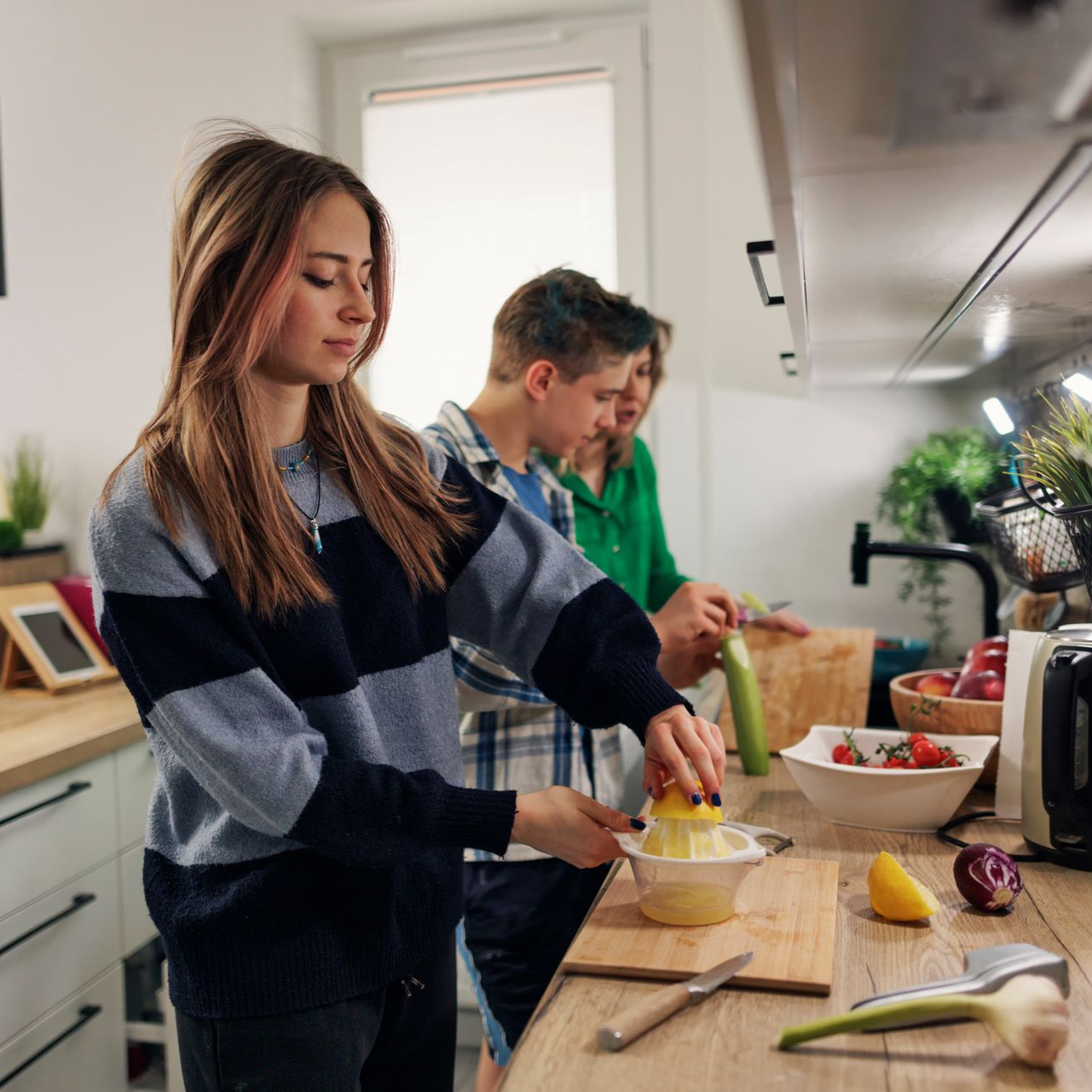 Two people preparing food in a bright kitchen, slicing and mixing ingredients on a counter.