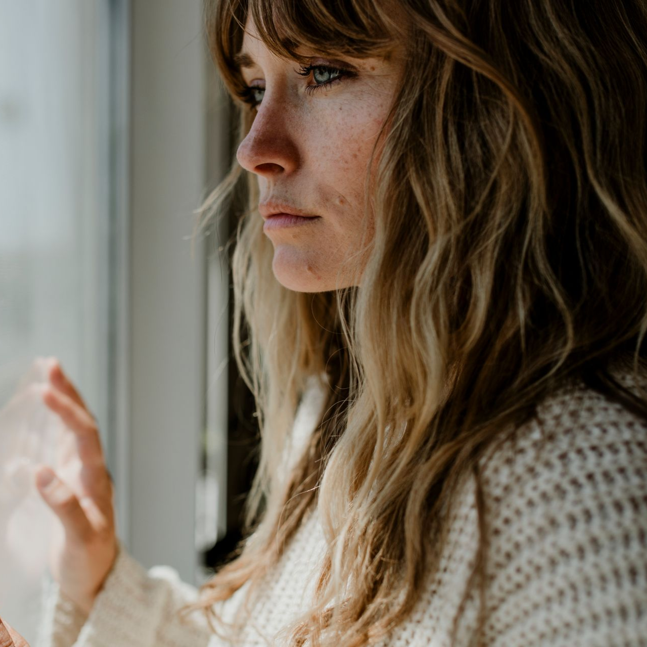 Woman looking out a window in deep thought
