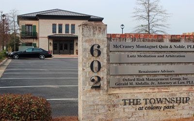 A brick sign for 602 The Township at Colony Park, showing a list of professional firms and a building in the background.