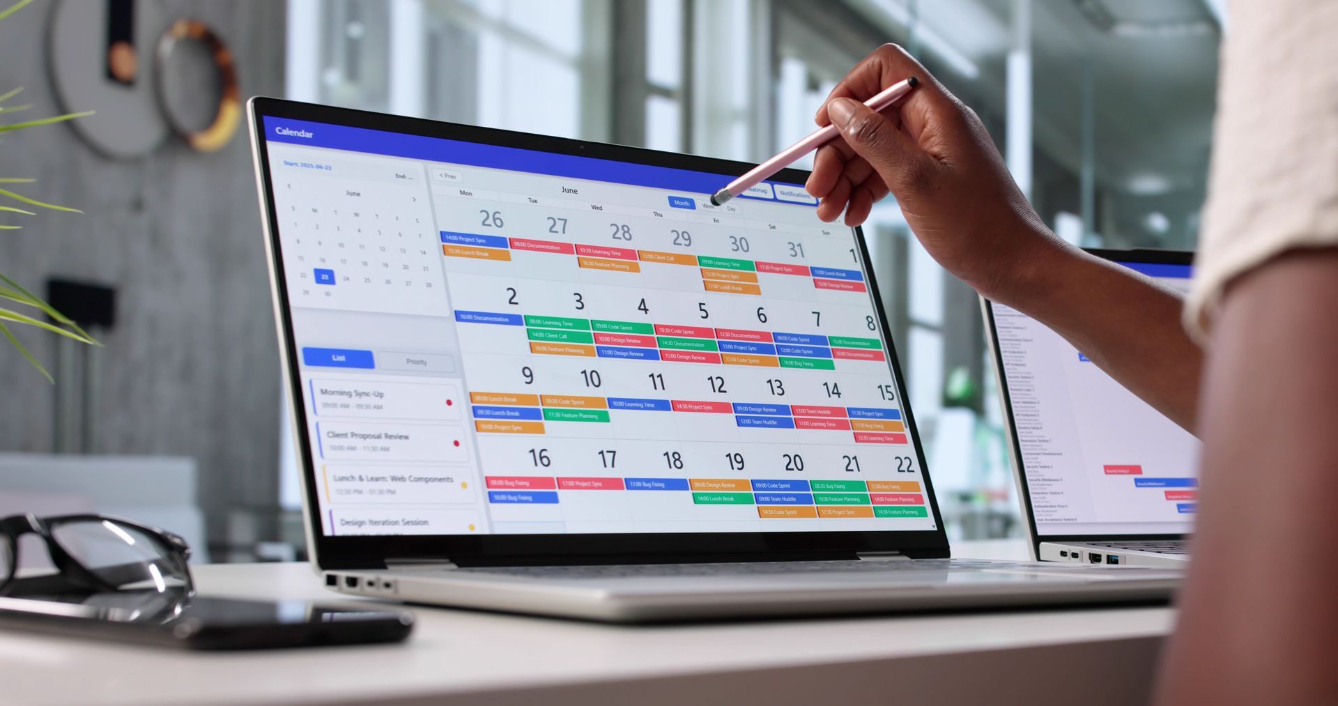 Person pointing at a calendar on a laptop screen, showing a schedule.