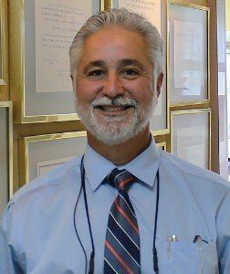 Dr. Rosado with a beard and tie is smiling for the camera.