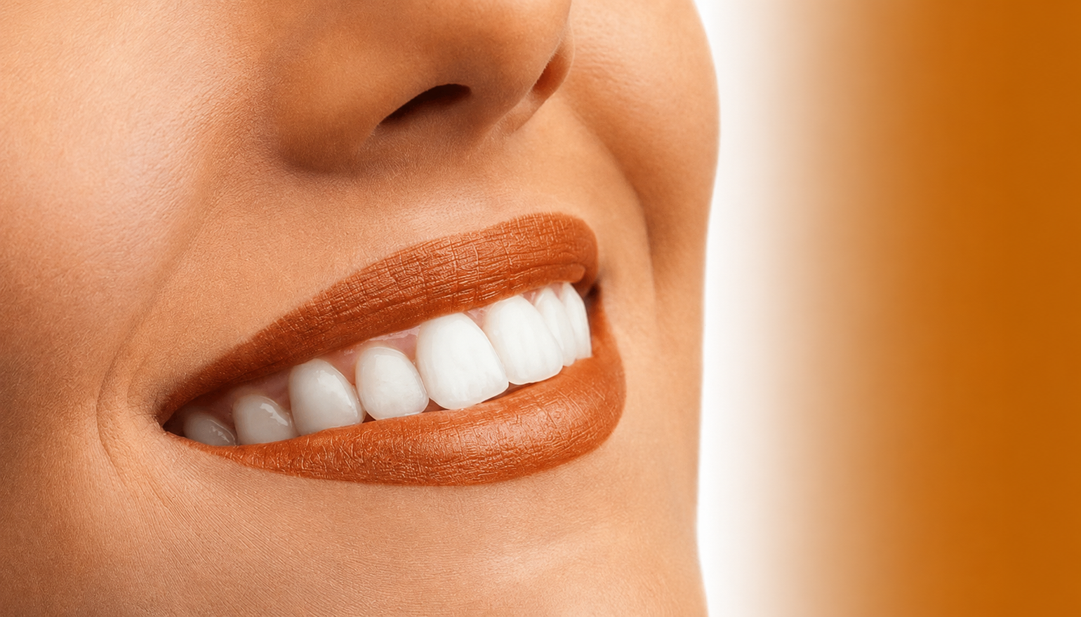 Close-up of a smiling mouth with orange lipstick and white teeth against an orange background