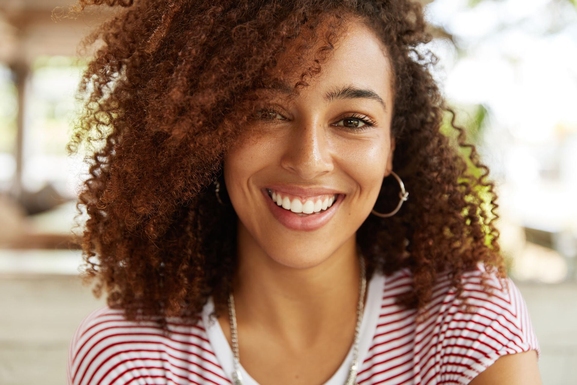 a woman with curly hair and hoop earrings is smiling for the camera