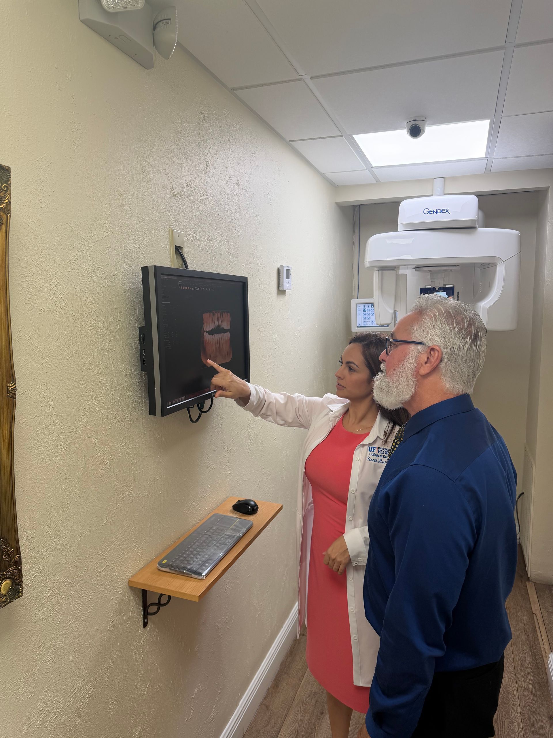 Dentist pointing at x-ray on monitor, explaining to a patient in a dental office.