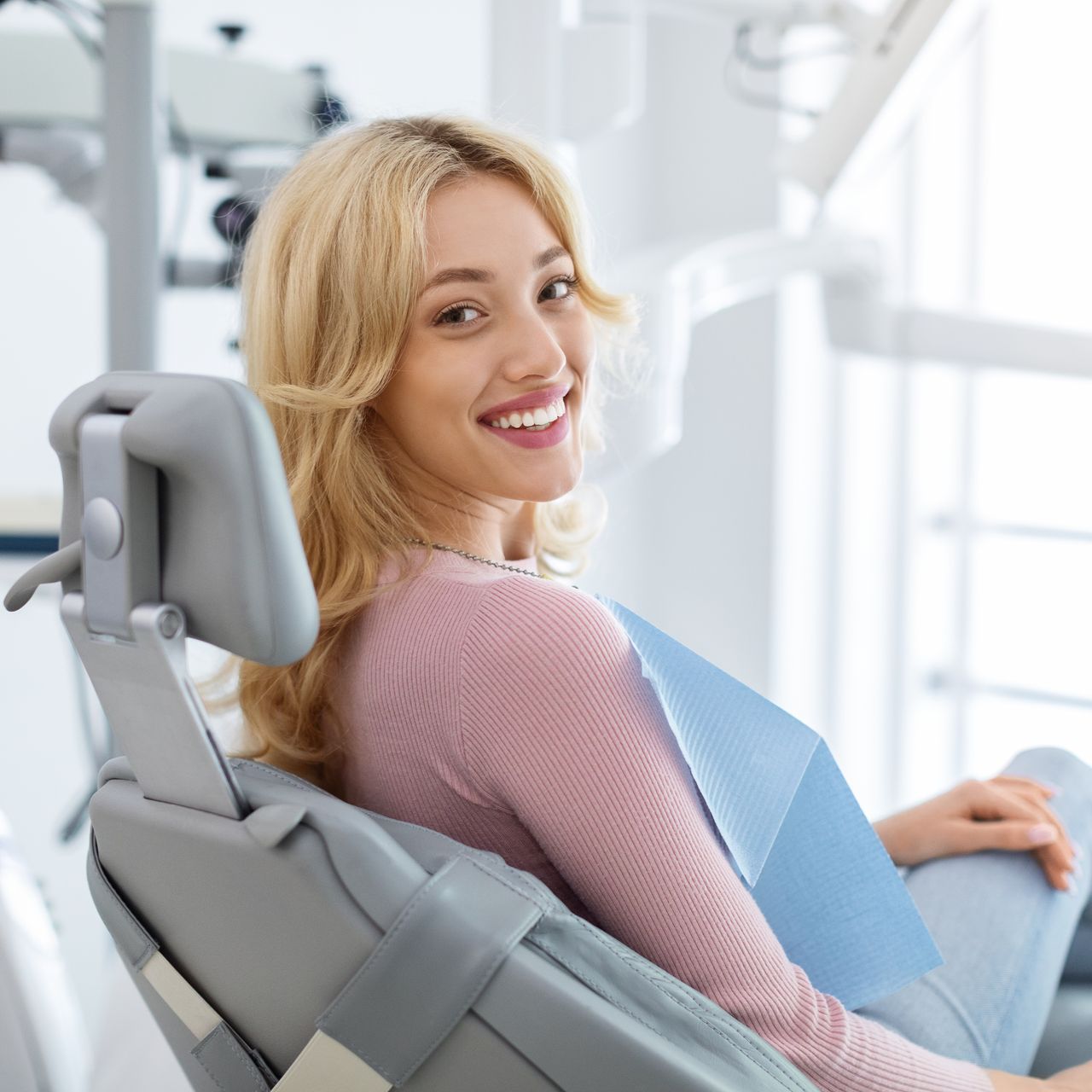 A woman is smiling while sitting in a dental chair