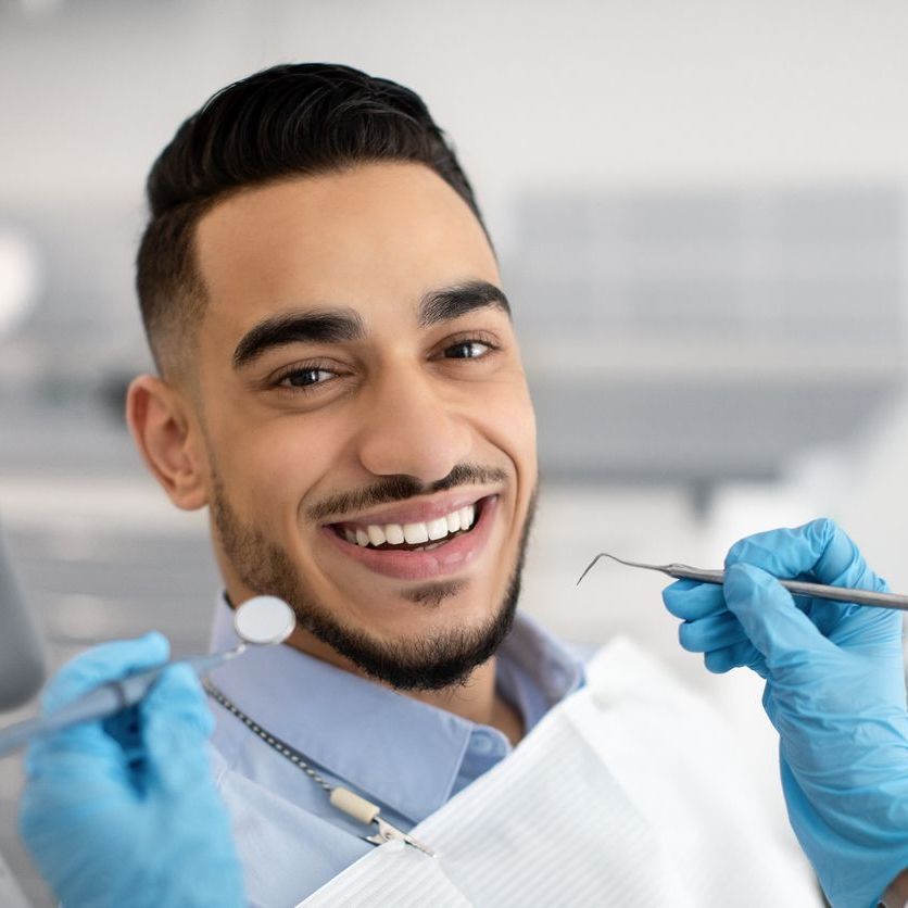 Un hombre sonríe mientras un dentista le examina los dientes.