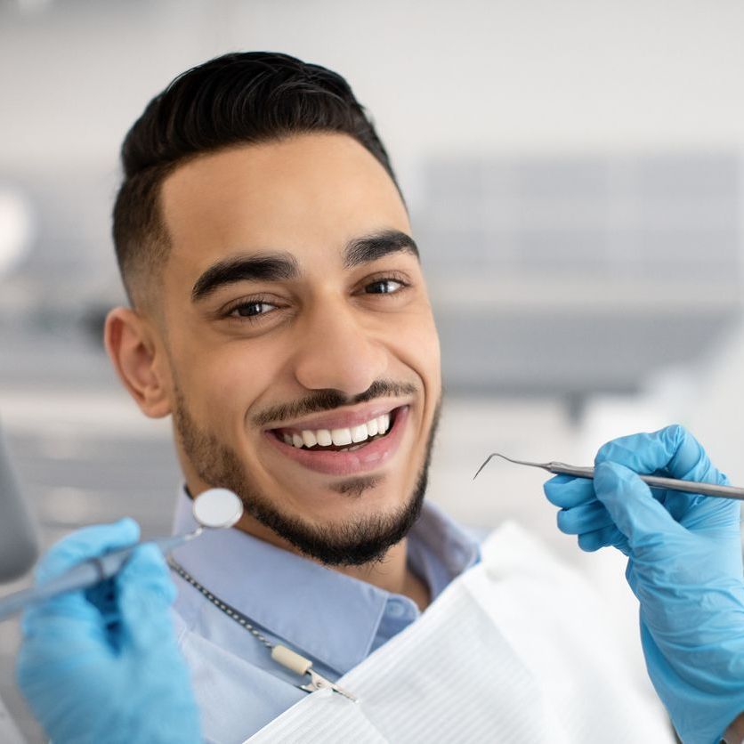 A man is smiling while sitting in a dental chair.