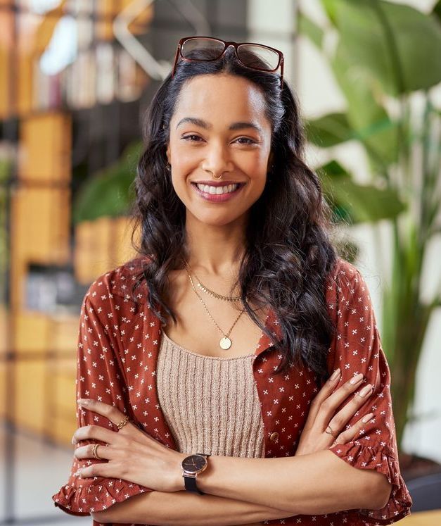 A woman is standing with her arms crossed and smiling.