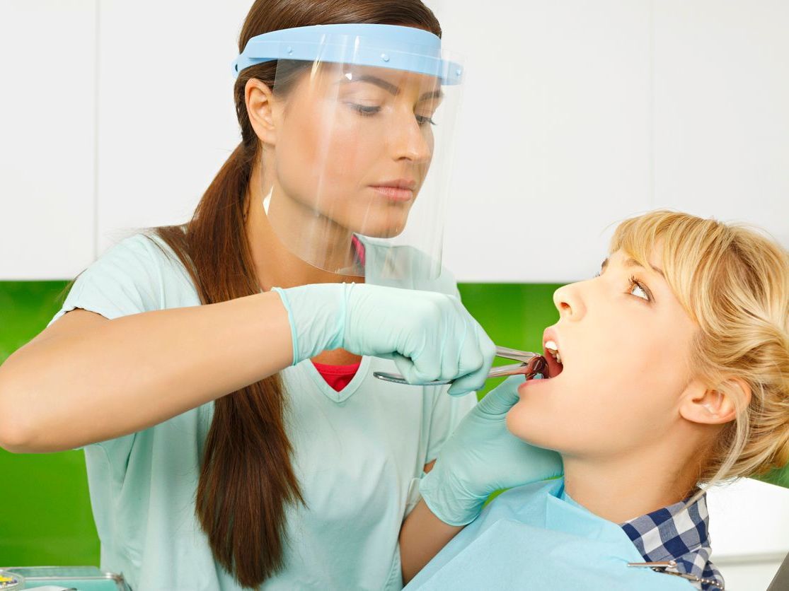 Una mujer se está haciendo examinar los dientes por un dentista.