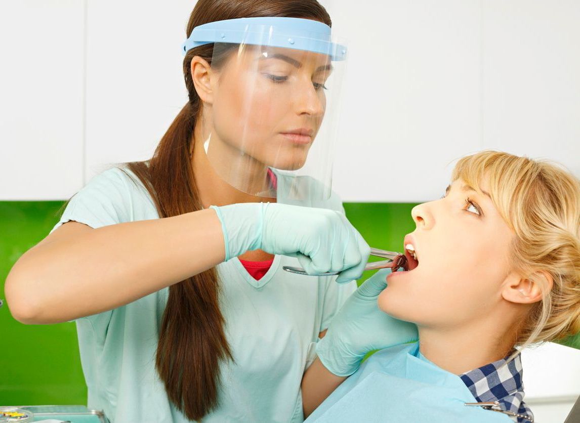 A woman is getting her teeth examined by a dentist.