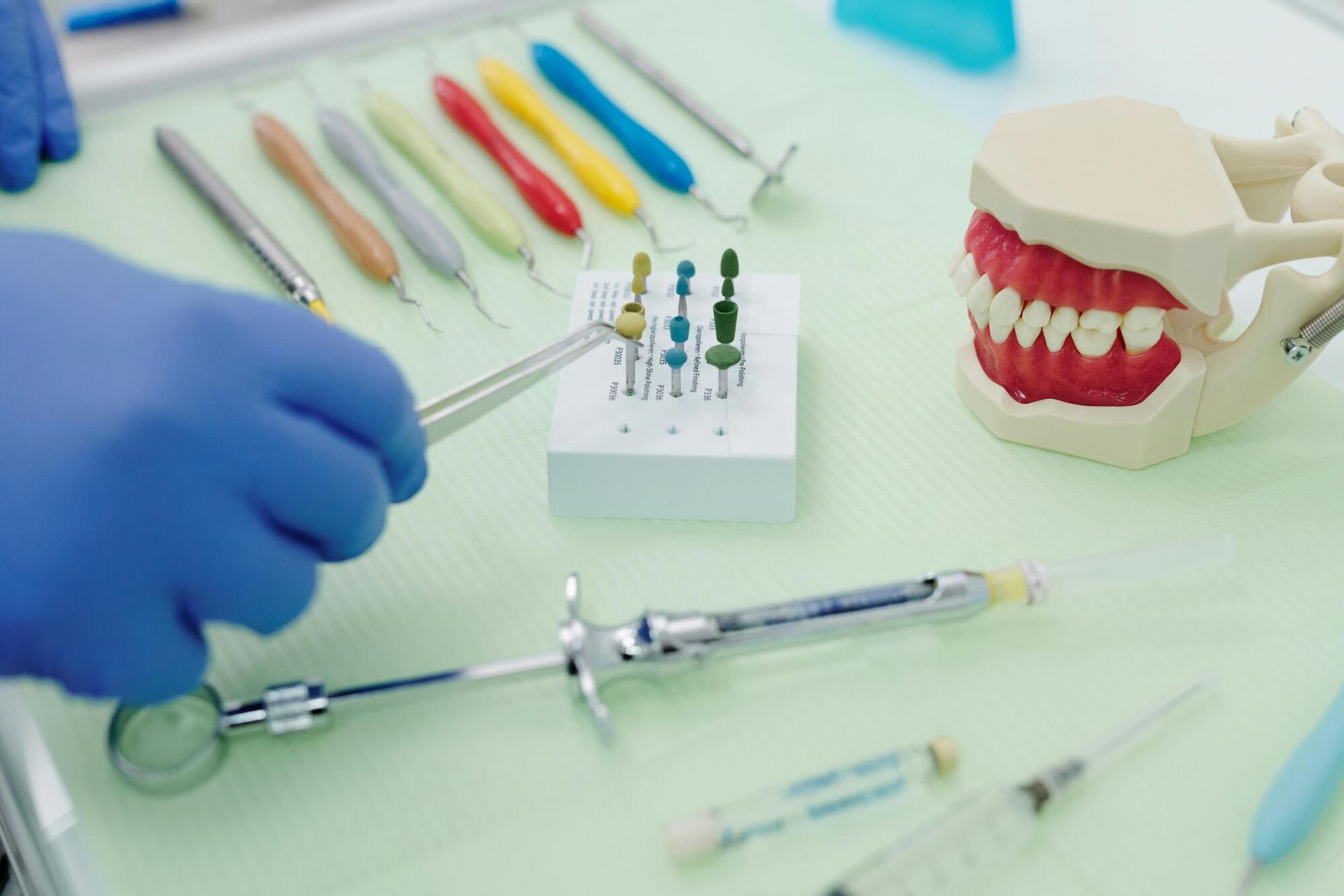 A dentist is holding a syringe in front of a model of teeth.