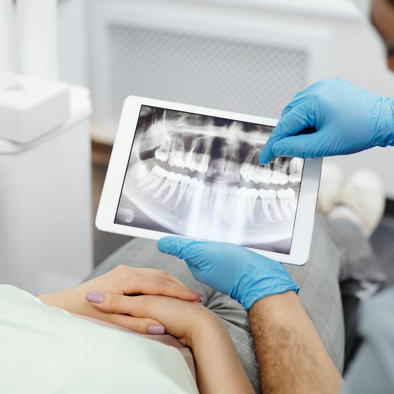 Un dentista está mirando una radiografía de los dientes de un paciente en una tableta.