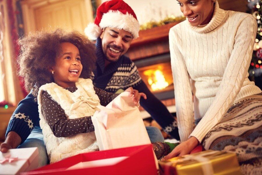 a family is opening christmas presents in front of a fireplace .