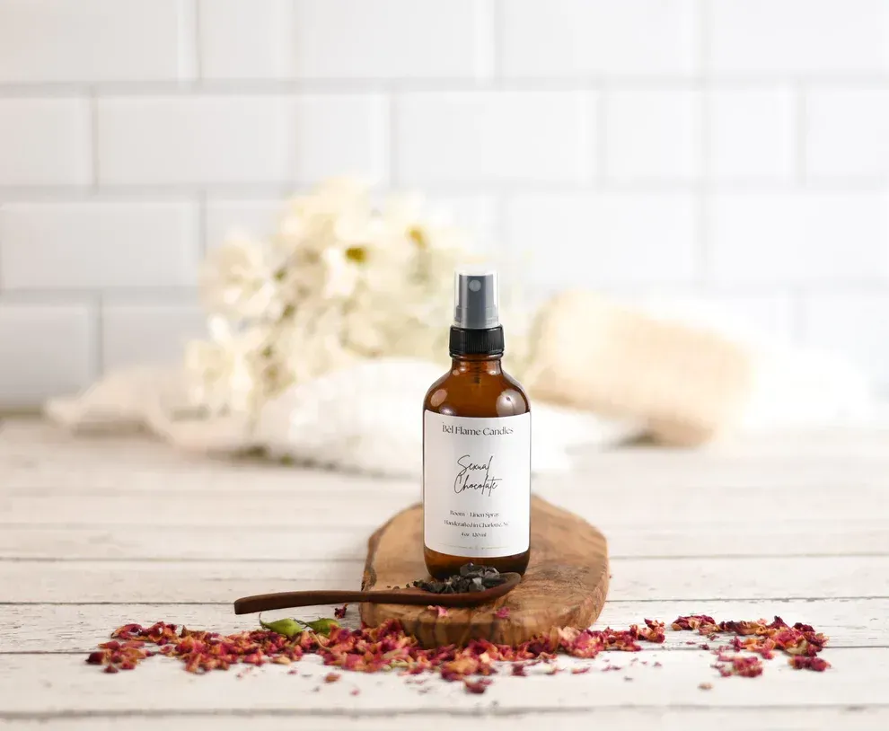 a spray bottle is sitting on a wooden cutting board with flowers in the background .