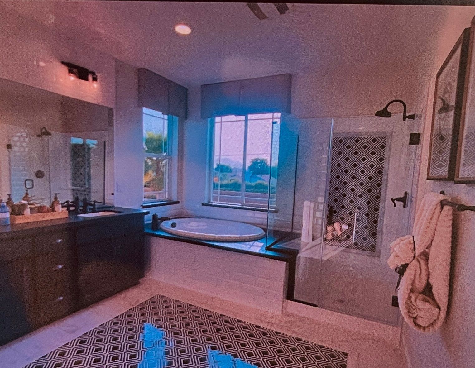 Luxurious bathroom with tub, shower, dark vanity, patterned rug, and window with a view.