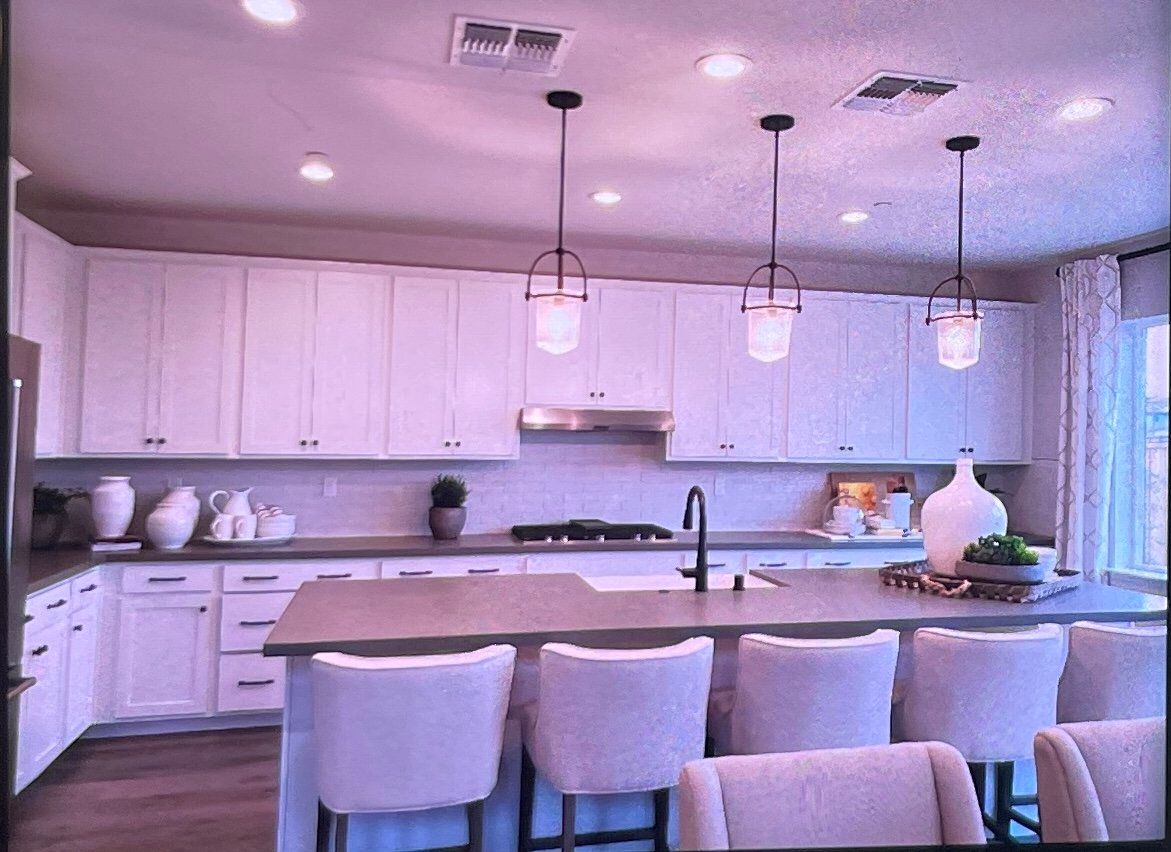 White kitchen with island, pendant lights, and bar stools.