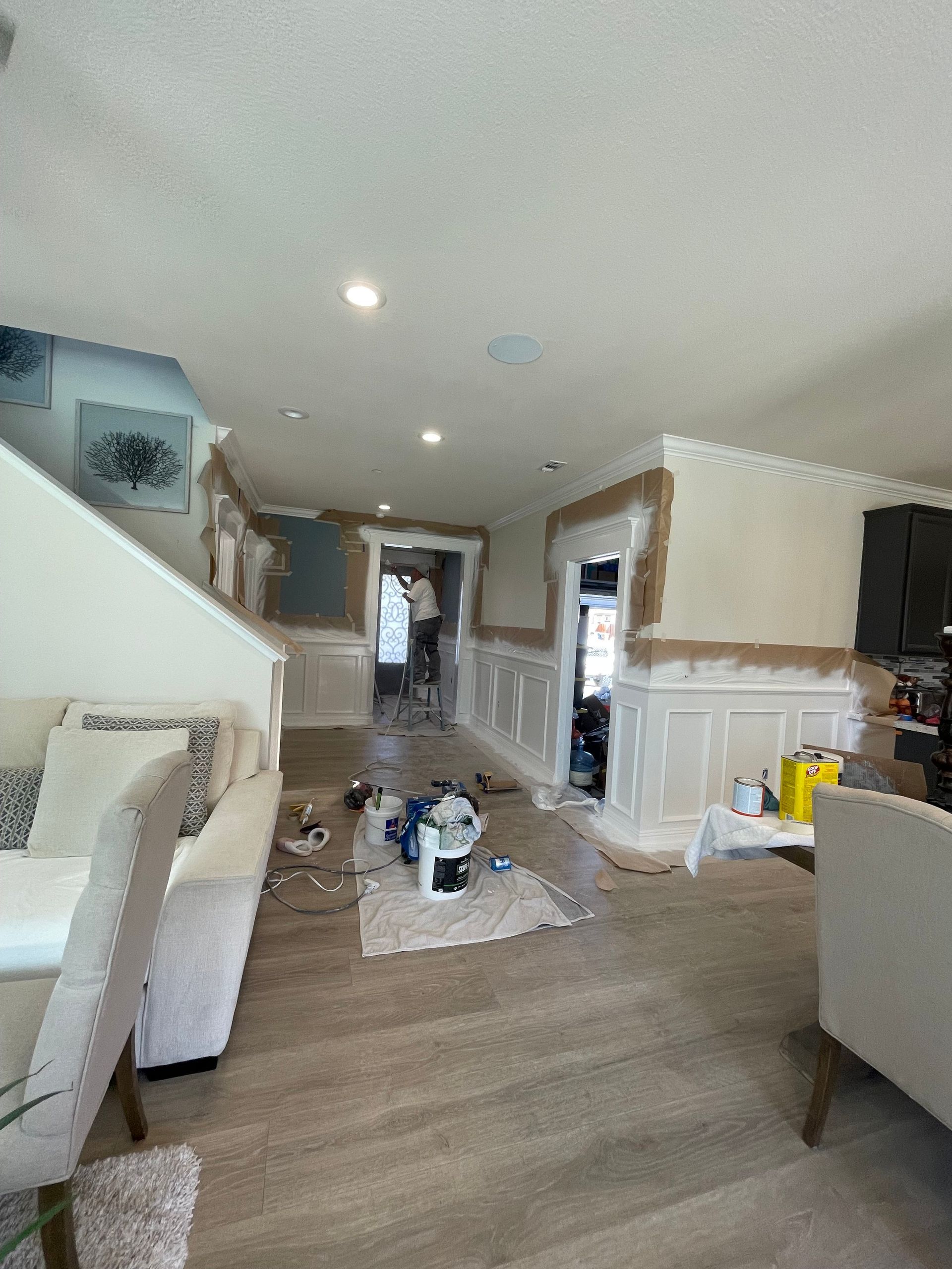 Interior renovation: Room with partially painted walls, protective coverings on floors, and tools.