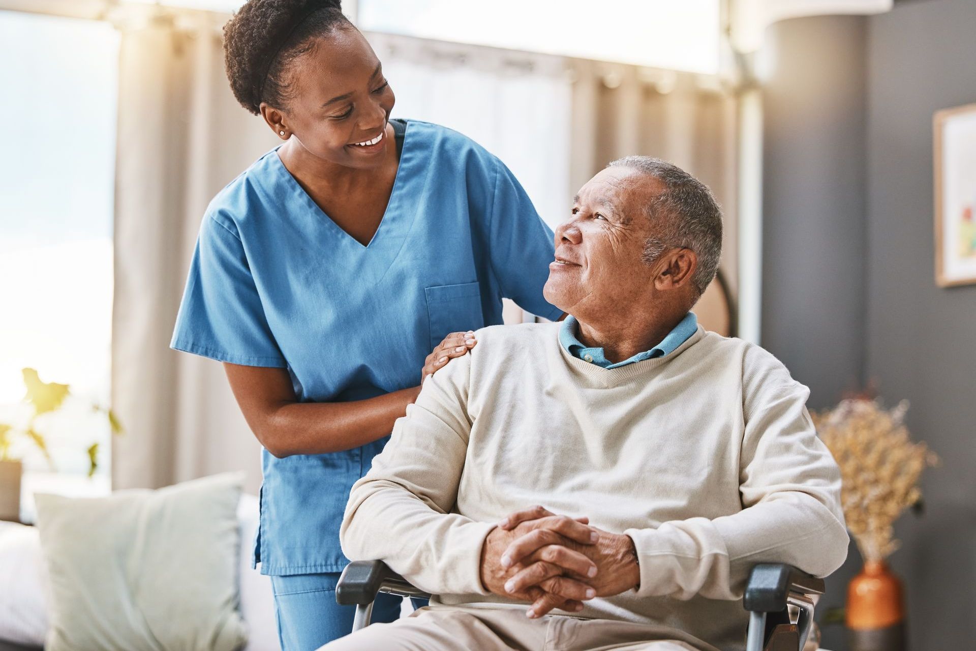 A nurse is standing next to an elderly man in a wheelchair.