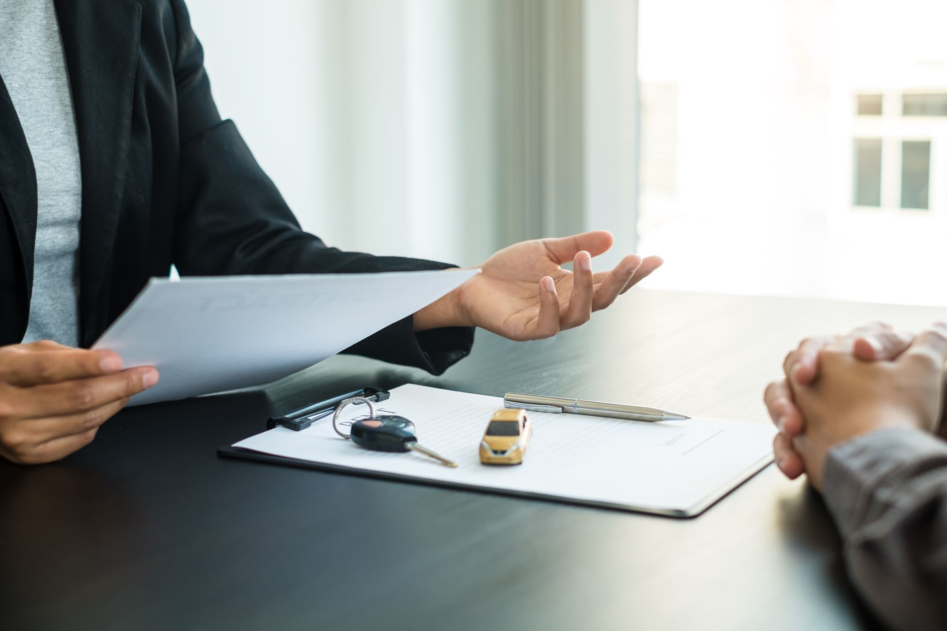 A woman is giving a car key to a man while sitting at a table.